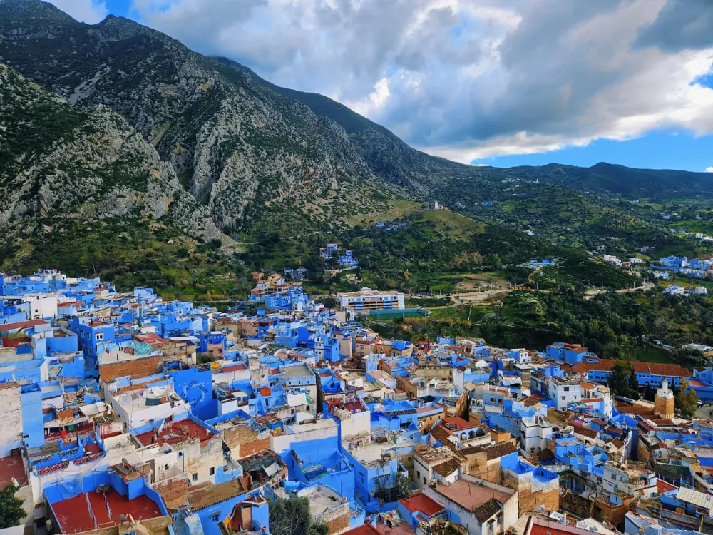 The blue houses of Chefchaouen spread below the green slopes of the Rif Mountains