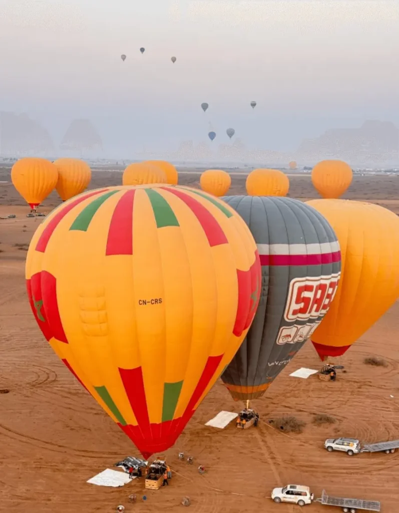 Hot-air balloons being inflated on the desert floor at dawn