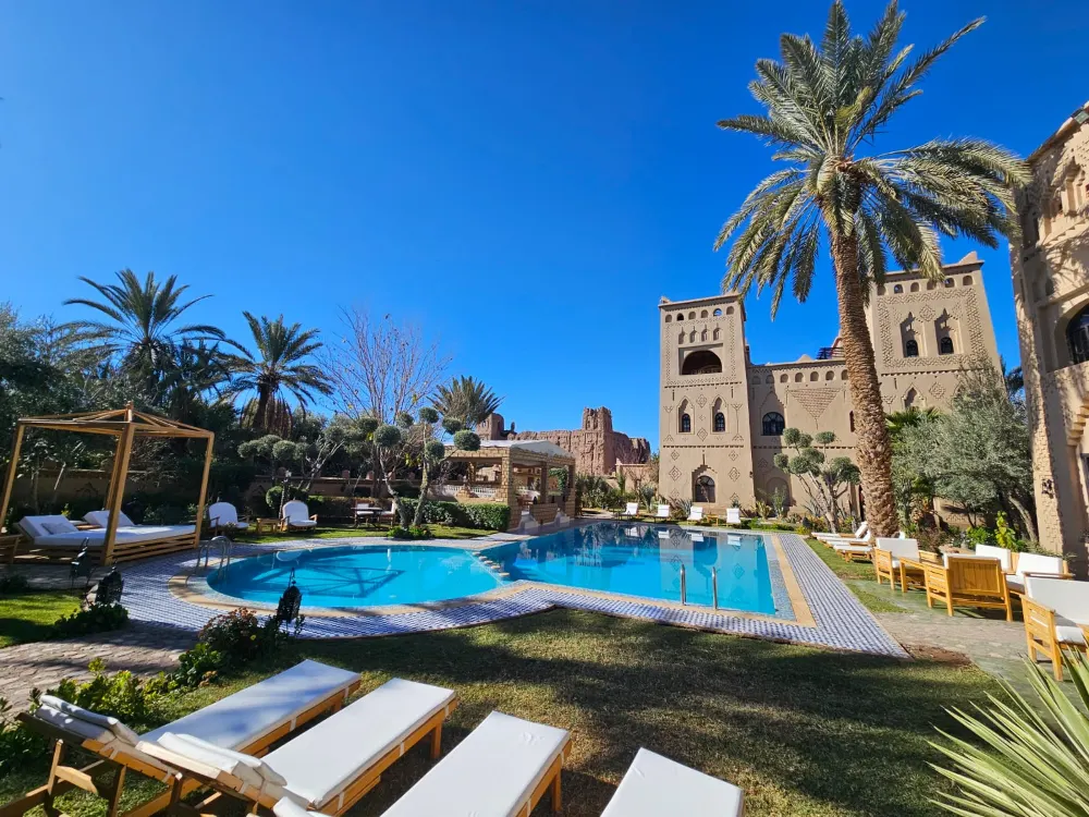 A pool framed by palms and lawns in the garden of a kasbah-style hotel in southern Morocco