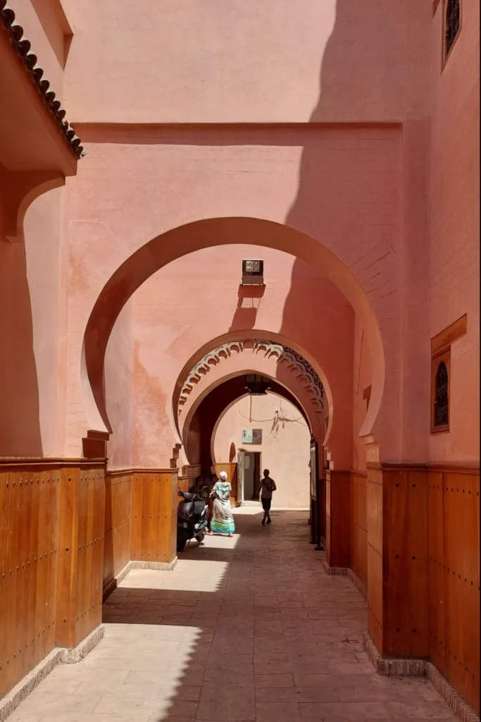 Pink horseshoe arches over a shaded passage in the Marrakech medina